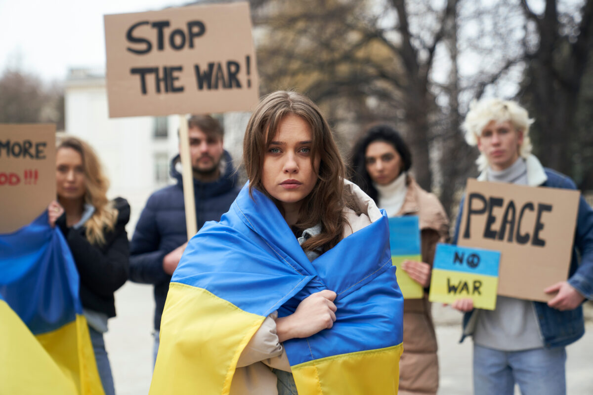 Girl wrapped in Ukrainian flag, protesting war